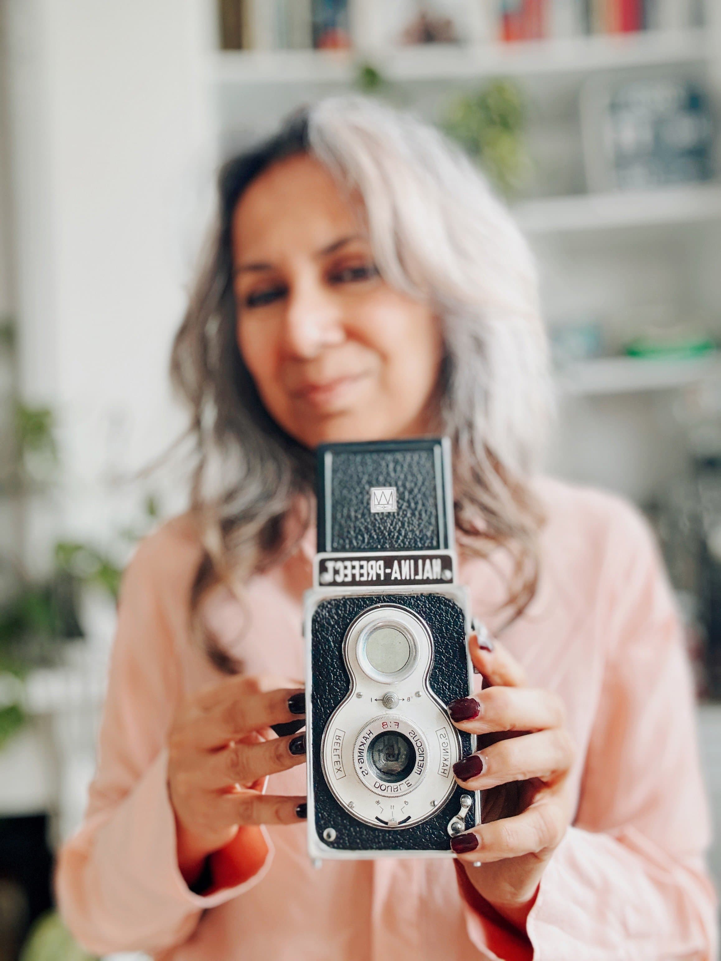 Razia Jukes, London personal branding photographer, holding a vintage twin-lens camera