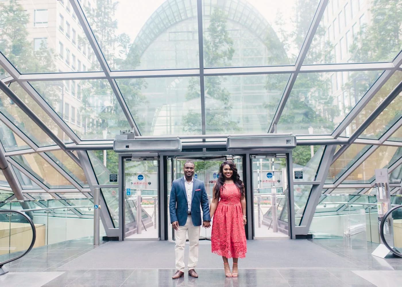 Couple photographed under the glass canopy at Crossrail Place, Canary Wharf, by Razia Jukes