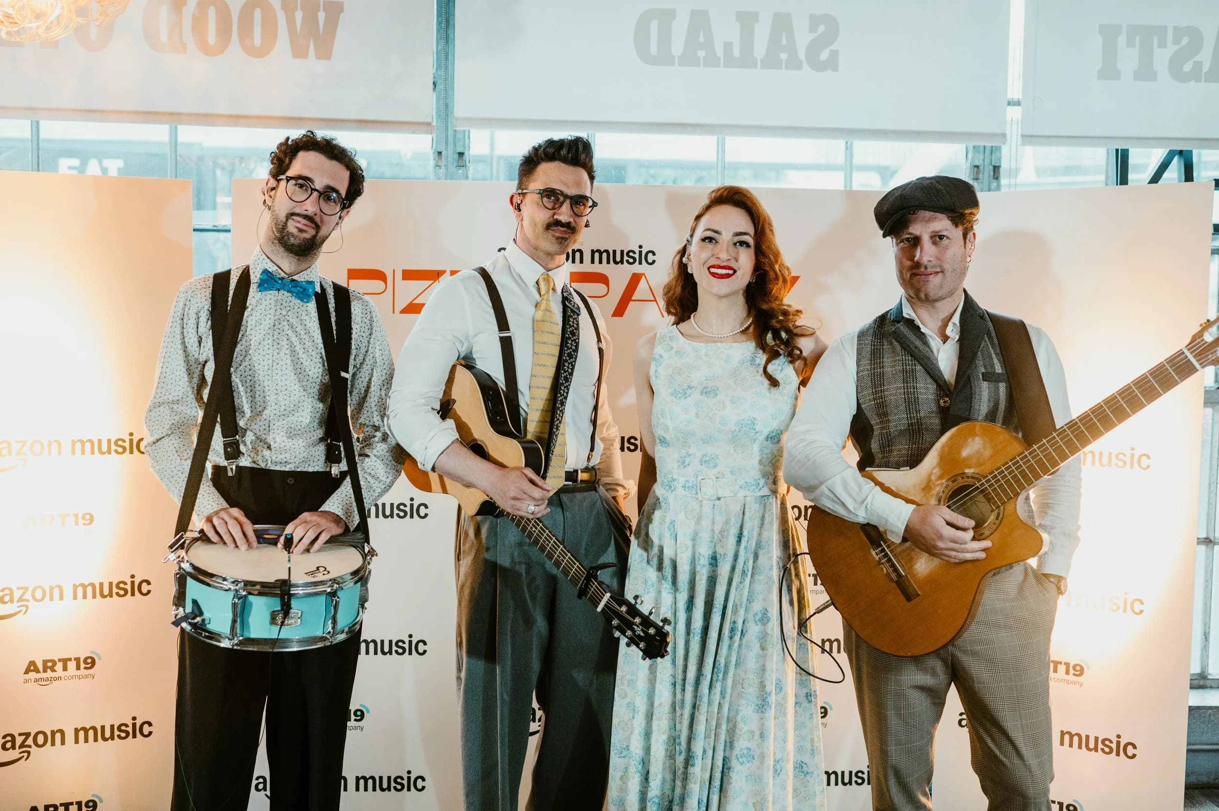 A four-piece band posing in front of an Amazon Music press wall