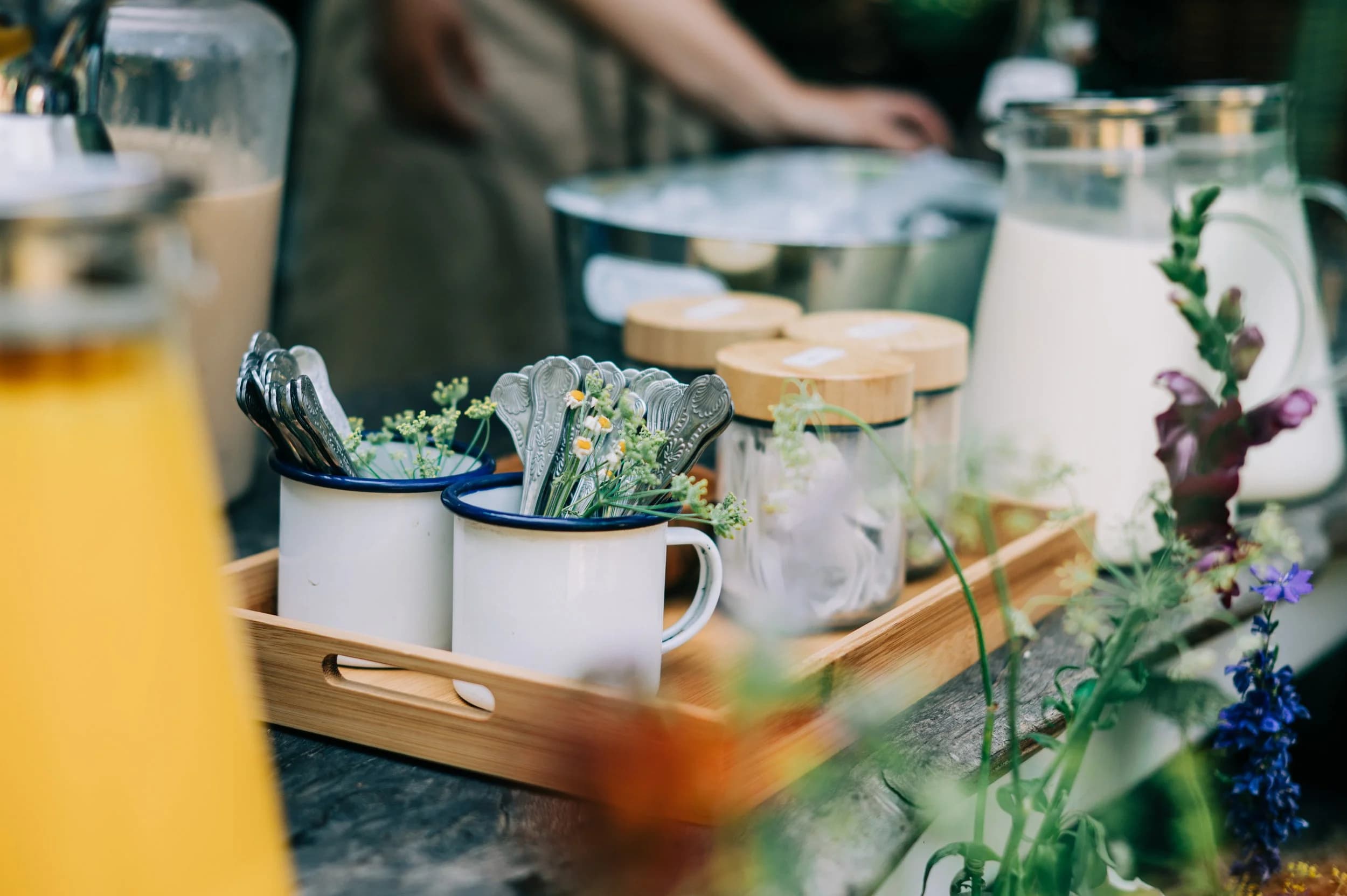 Enamel mugs, napkins and jugs of juice on a serving table