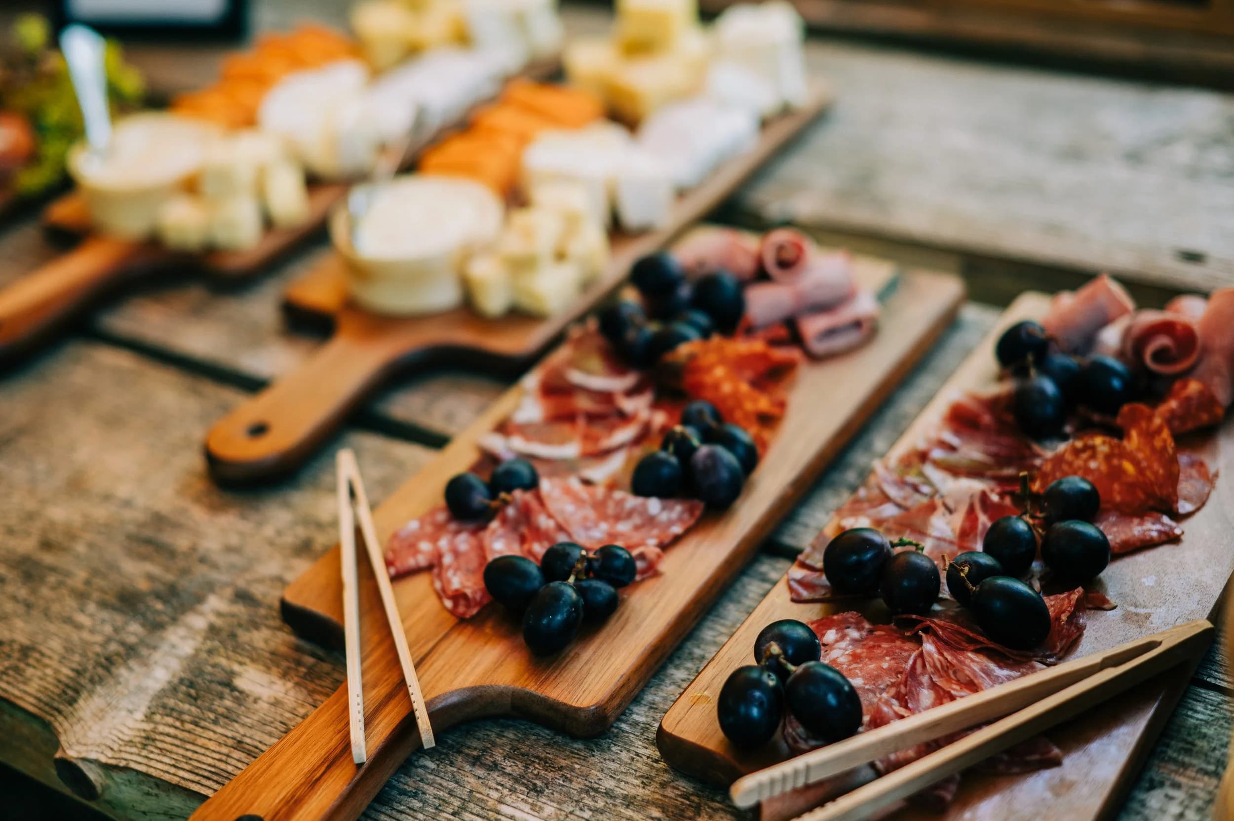 Boards of cured meats, olives and cheese on a wooden table