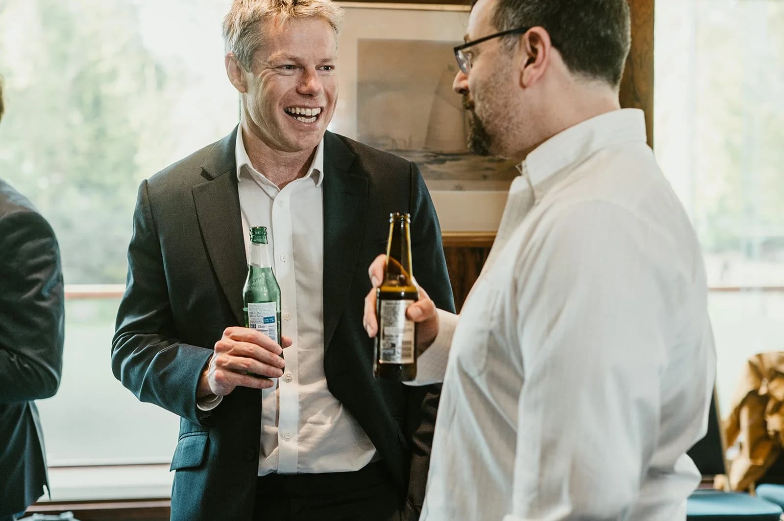 Two men laughing together over bottles of beer