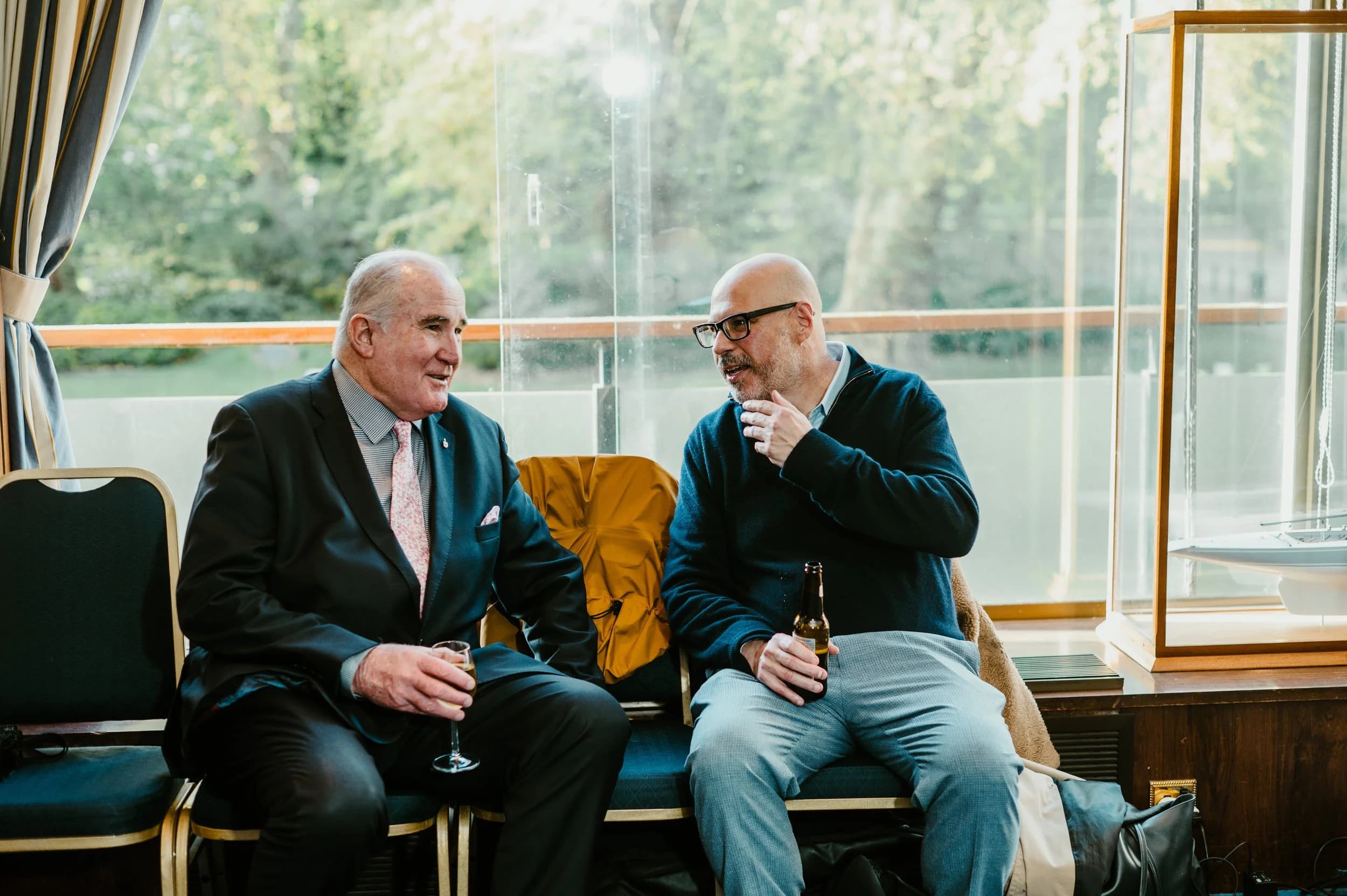 Two men in suits in conversation beside a window at a London members’ club