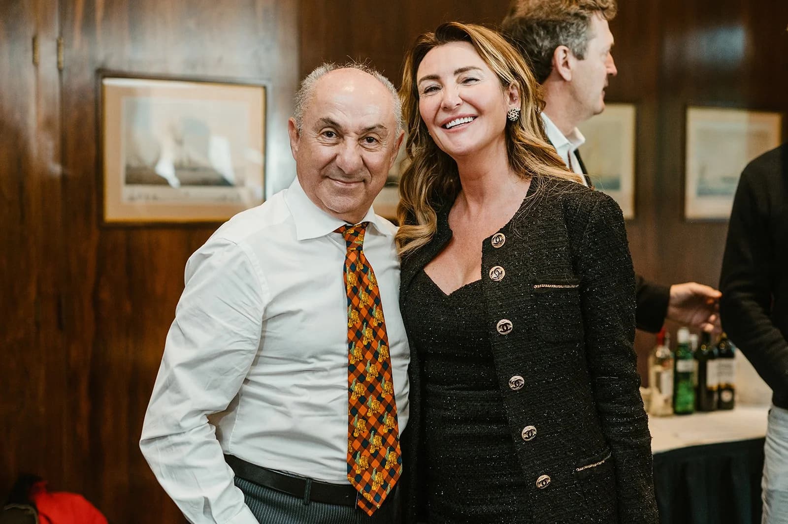 A man in a white shirt and checked tie posing with a smiling woman in a black jacket
