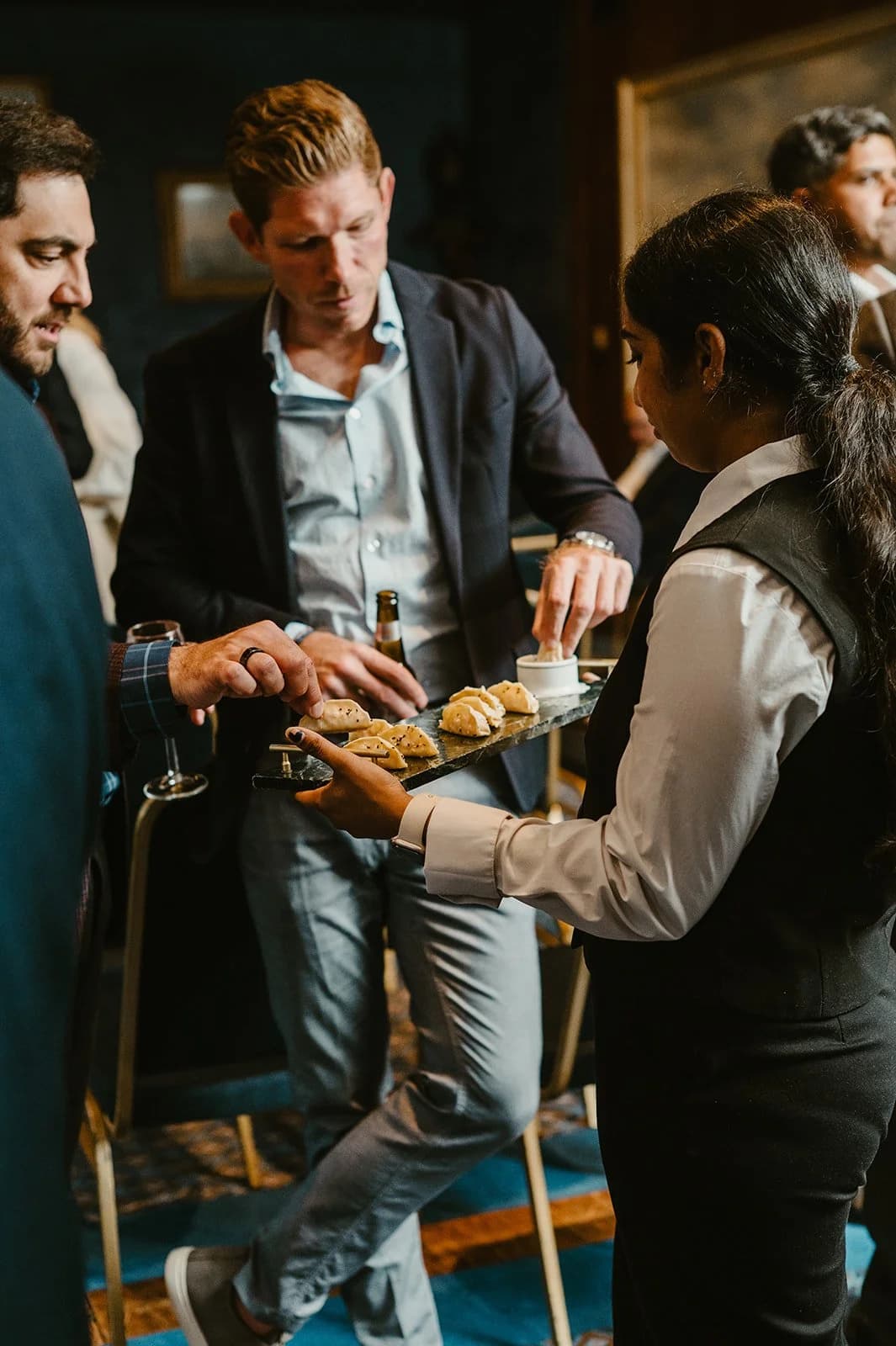 A waitress offering a tray of canapes to guests at a reception