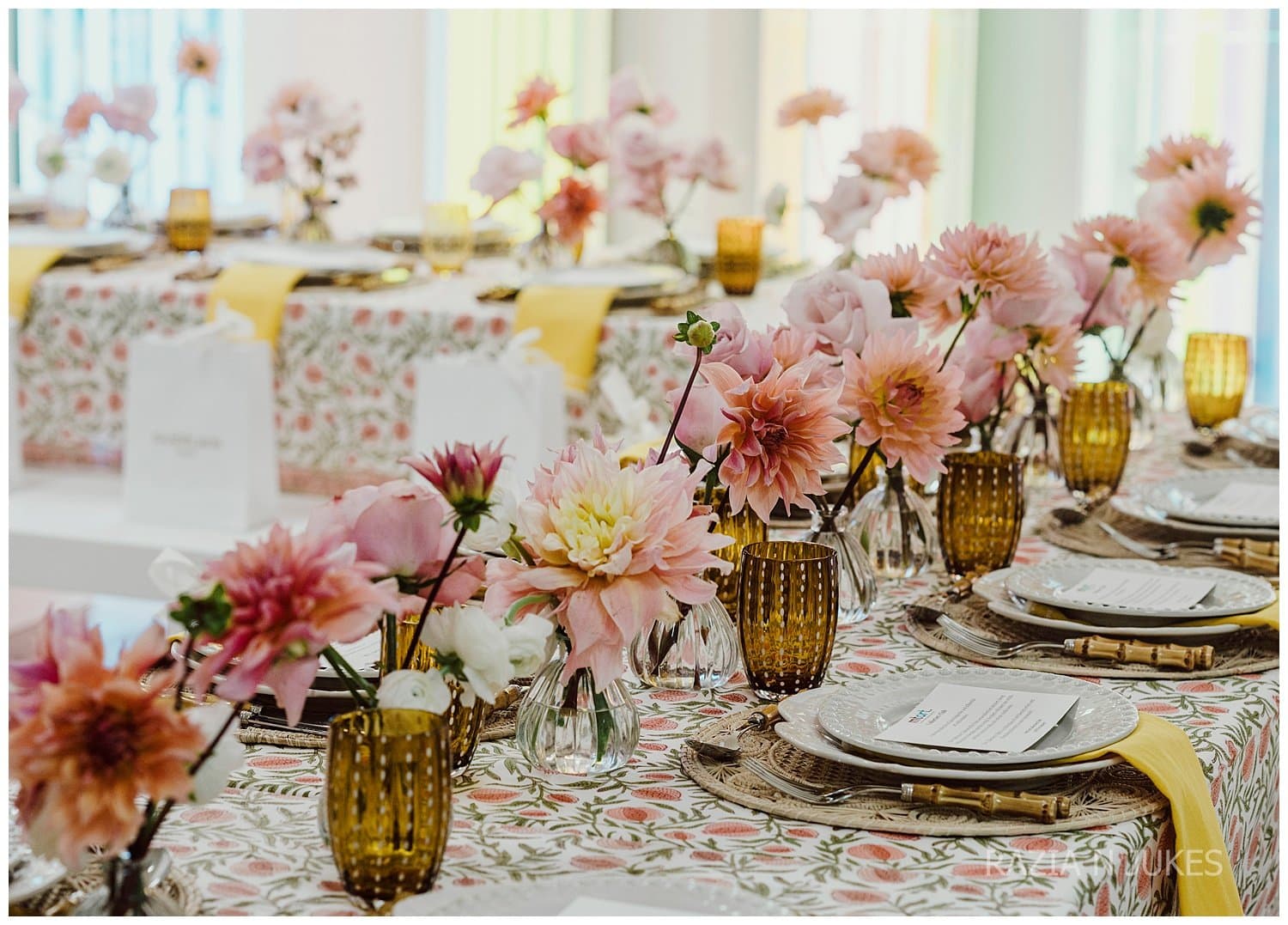 A table laid with pink dahlias, amber glasses and patterned linen