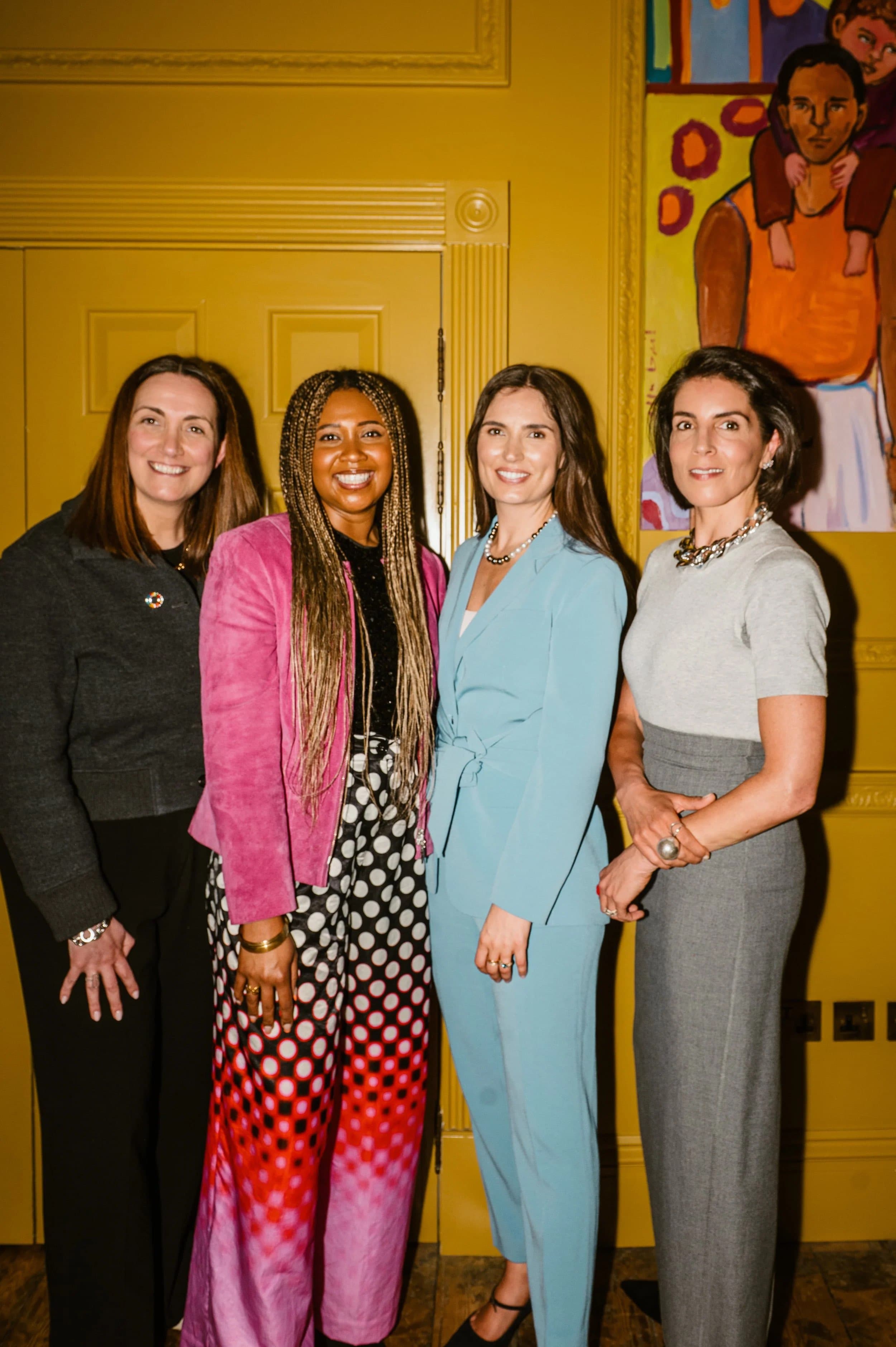 Four women posing in front of artwork at a founder-led launch event