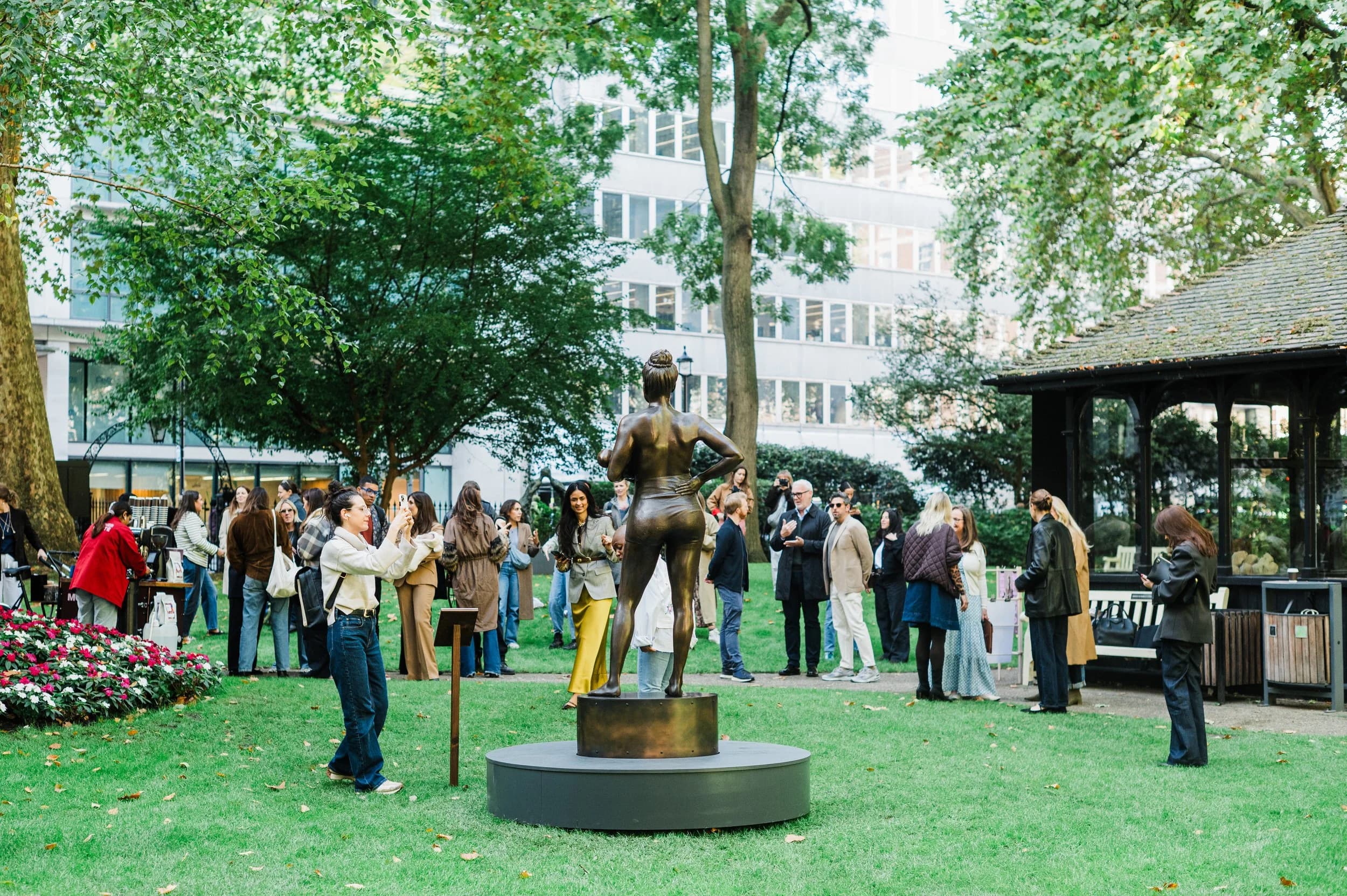 Guests gathered around a bronze sculpture in a London garden square