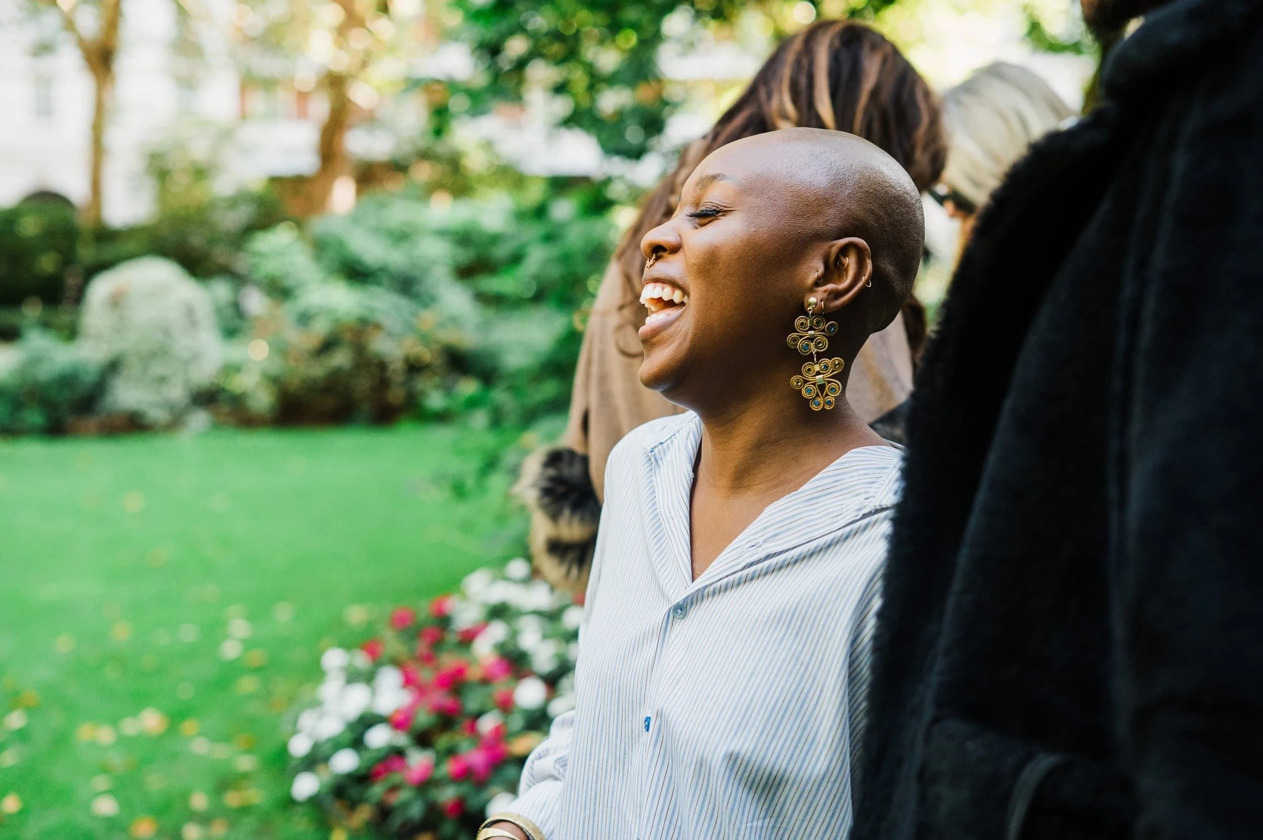 A woman laughing in a garden at an outdoor reception