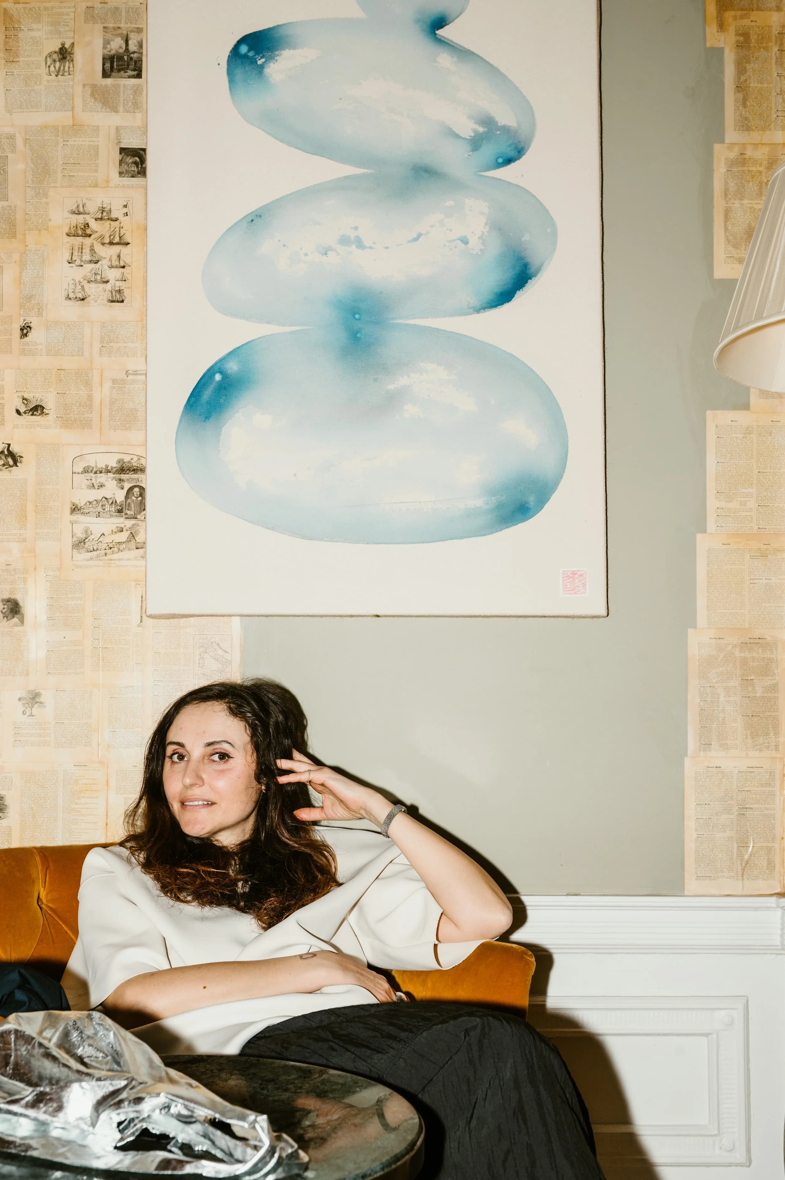 A woman relaxing in an armchair beneath a blue abstract painting