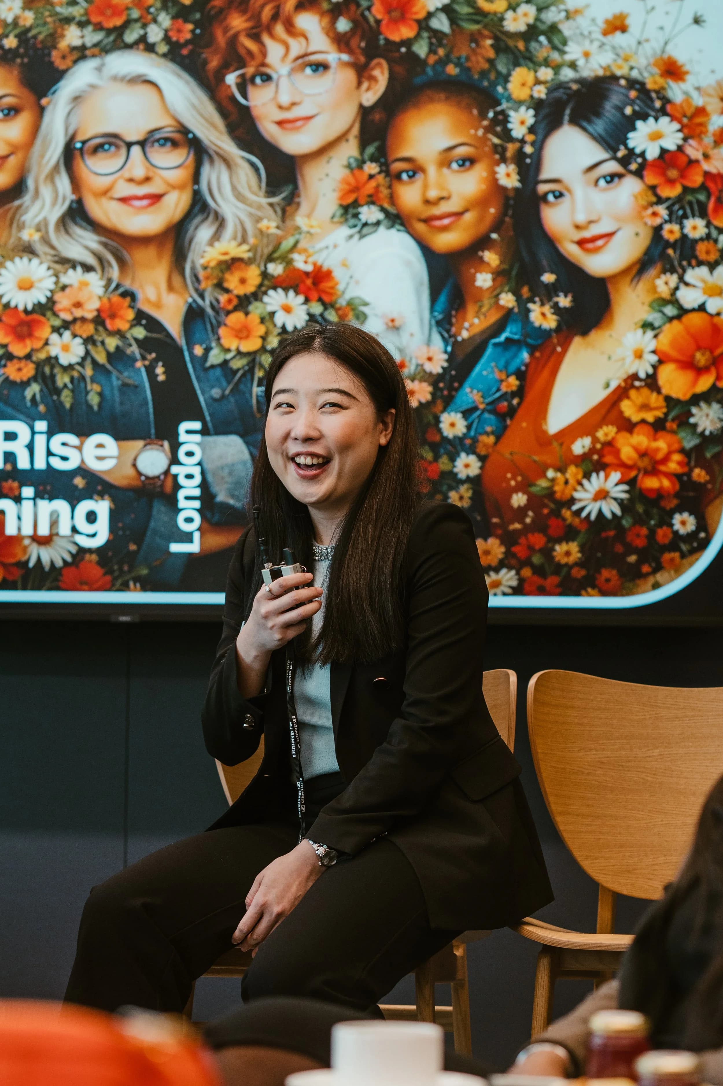 A guest laughing in front of a colourful illustrated screen at a networking event