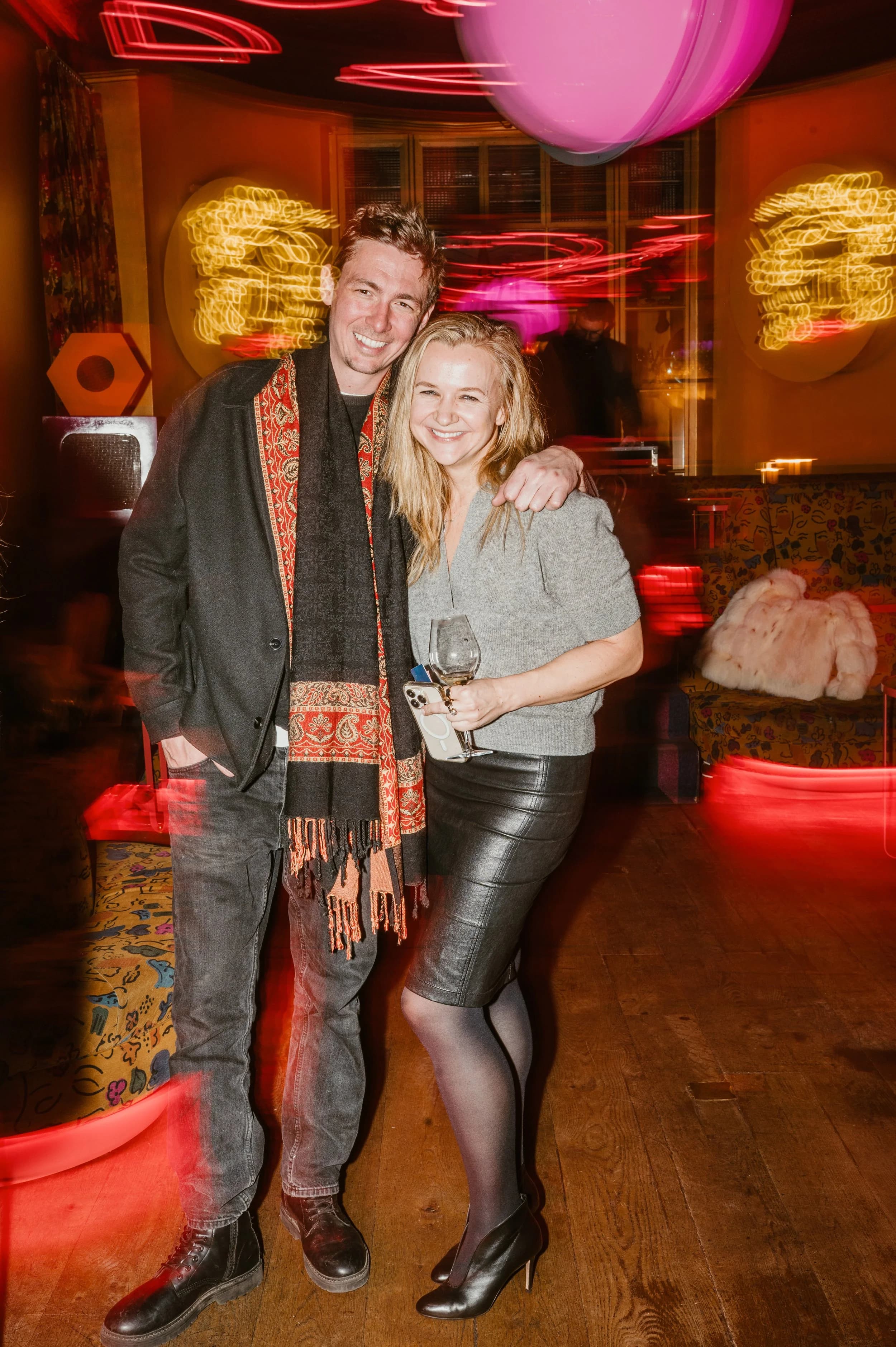 A couple posing under neon lights at a party