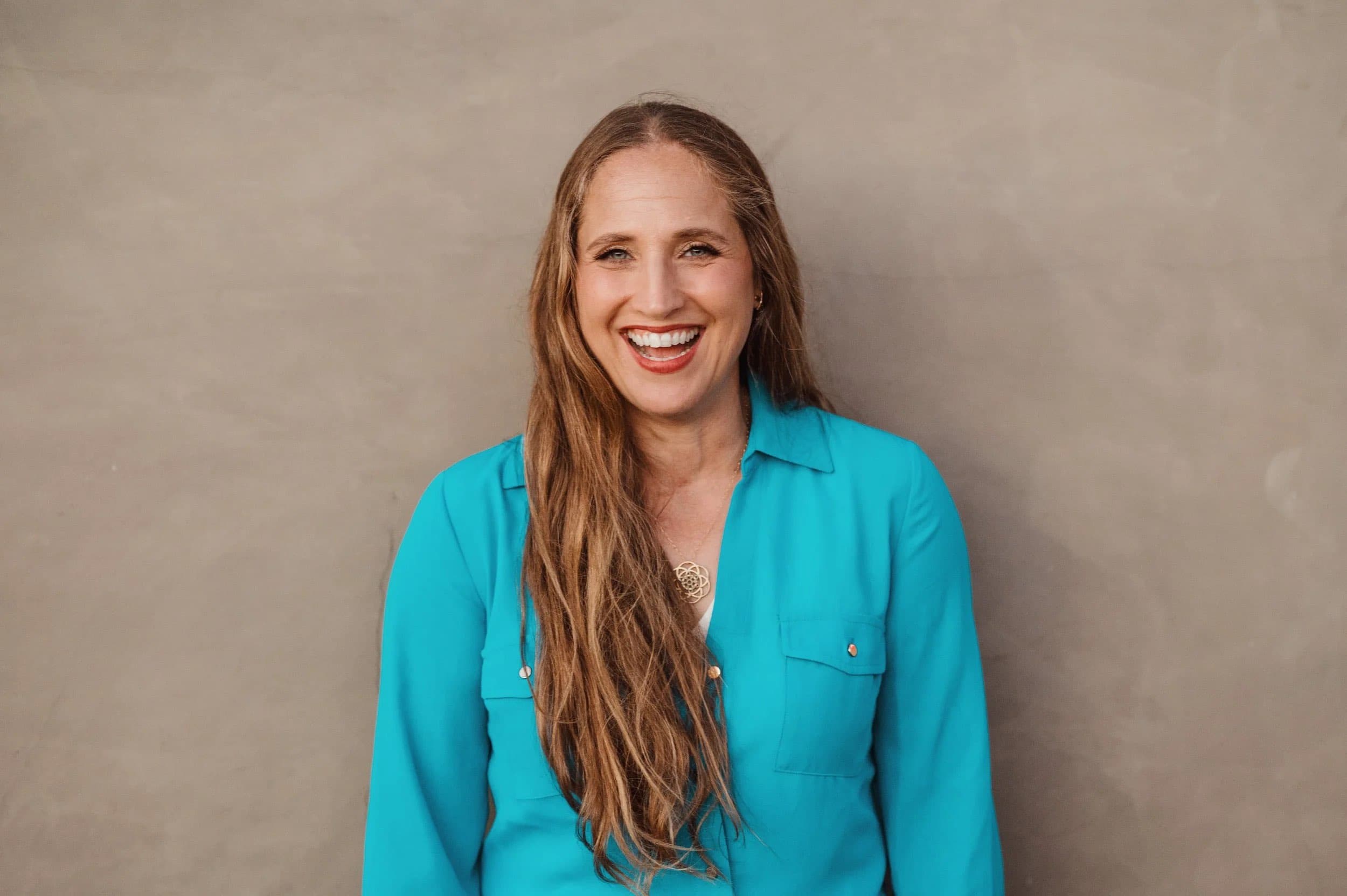 A smiling woman with very long hair in a turquoise shirt