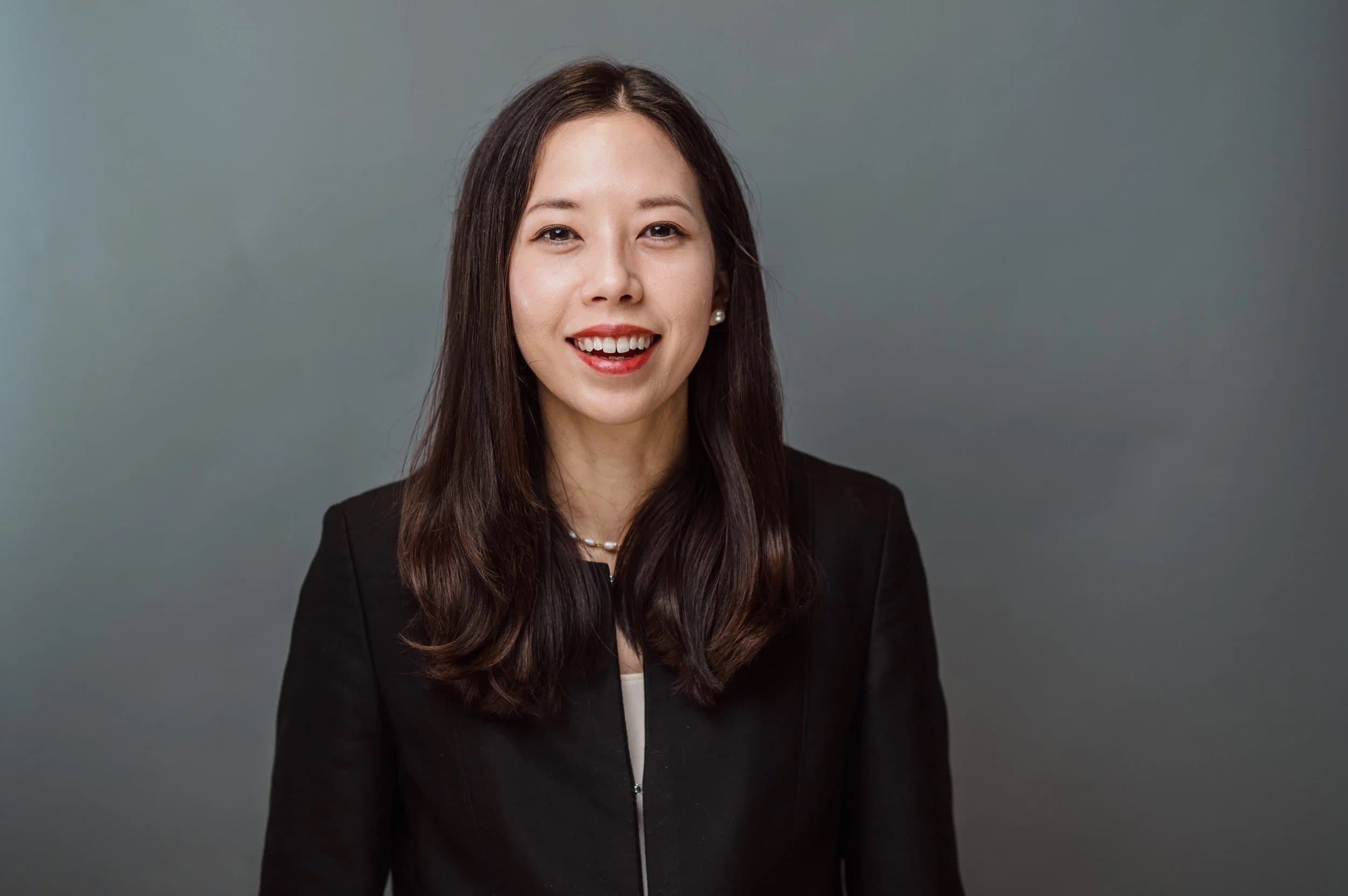 Headshot of a smiling woman with long dark hair in a black jacket