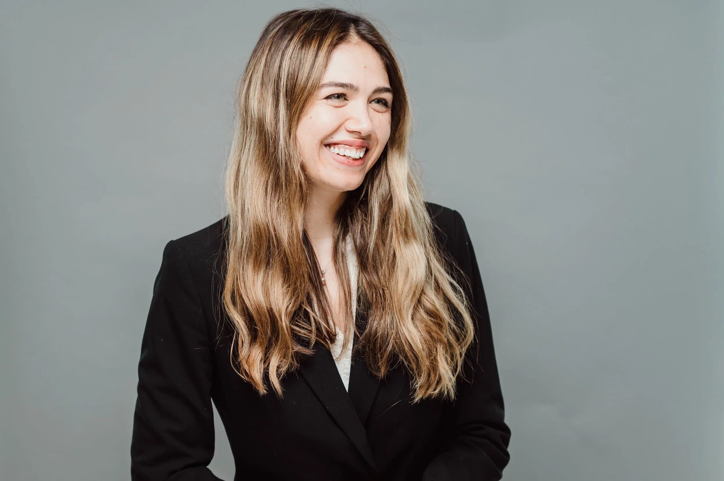 A smiling woman with long blonde hair in a black blazer