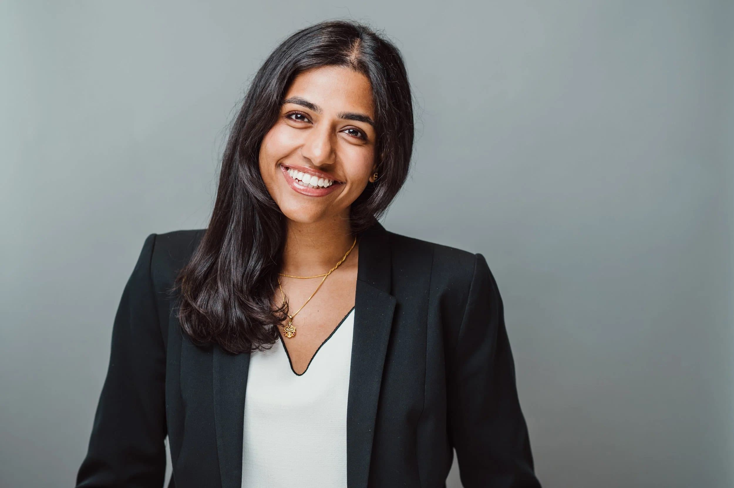 Studio LinkedIn headshot of a smiling woman in a black blazer