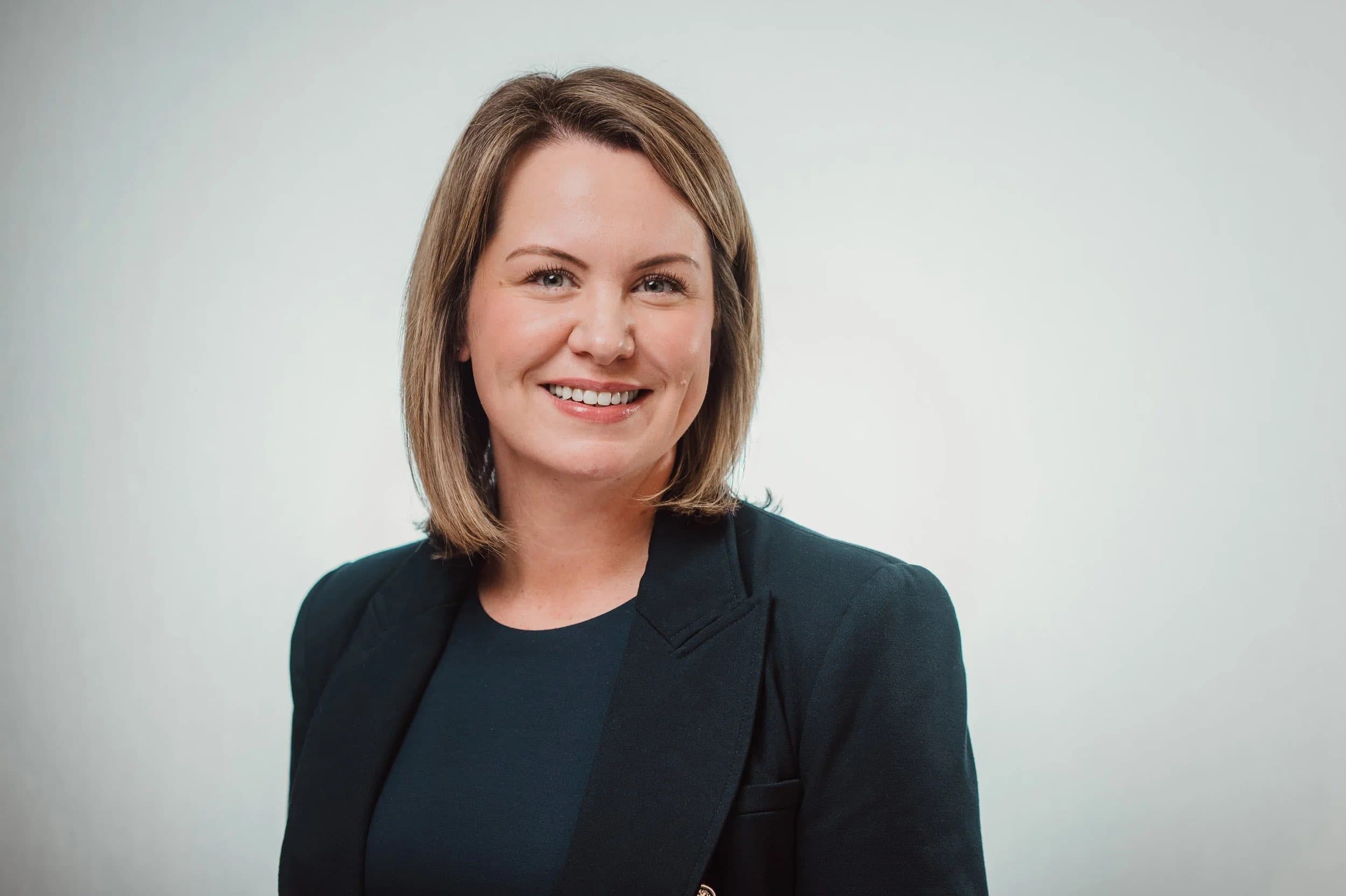 Headshot of a smiling woman with a bob in a navy blazer